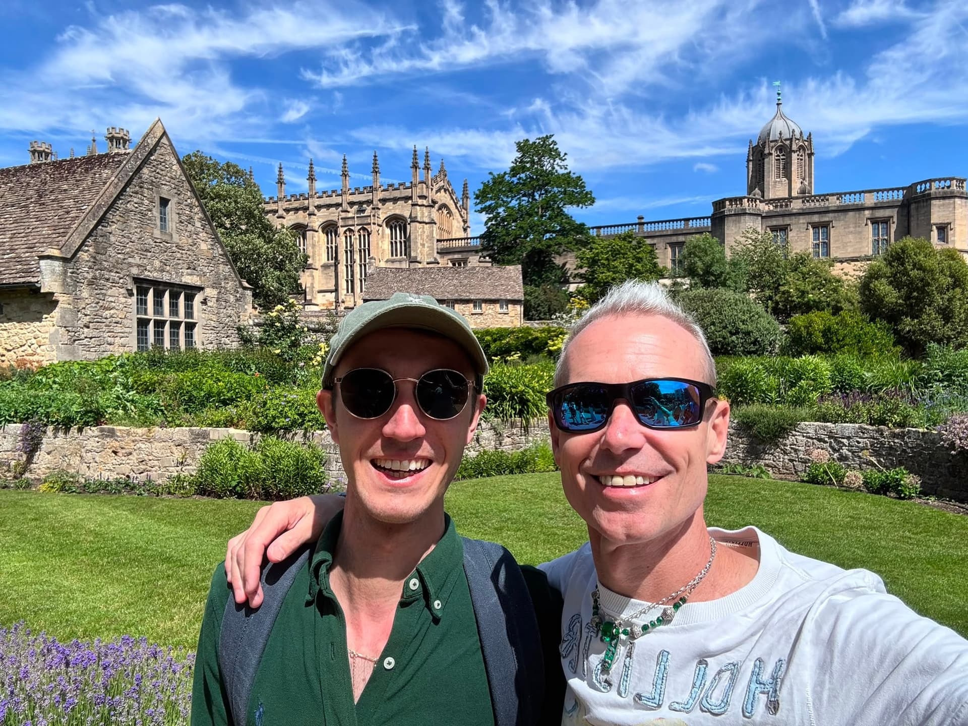 Two friends pause in front of an Oxford college on a sunny walk.