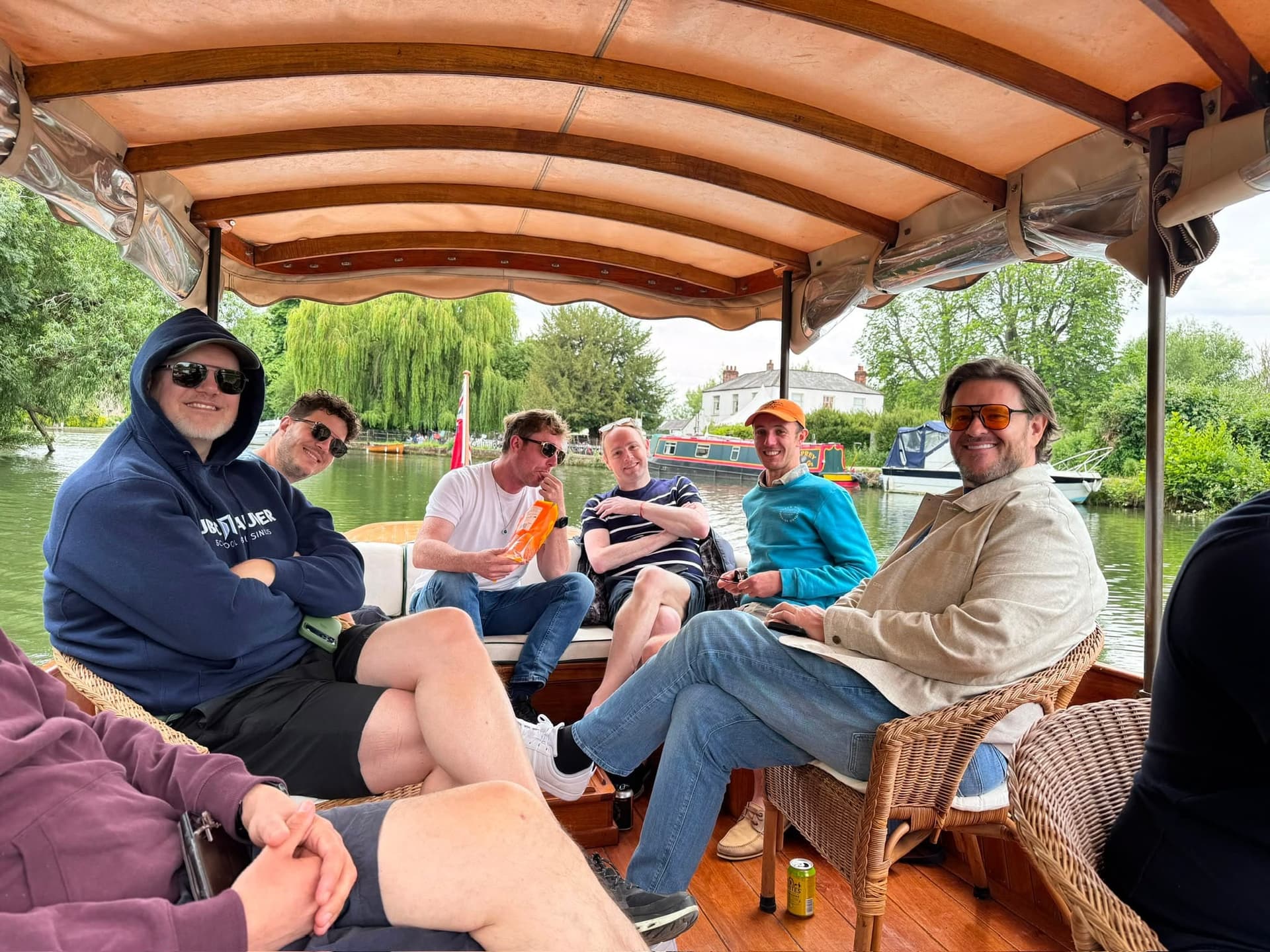 Friends relax together on a punt beneath a striped canopy.