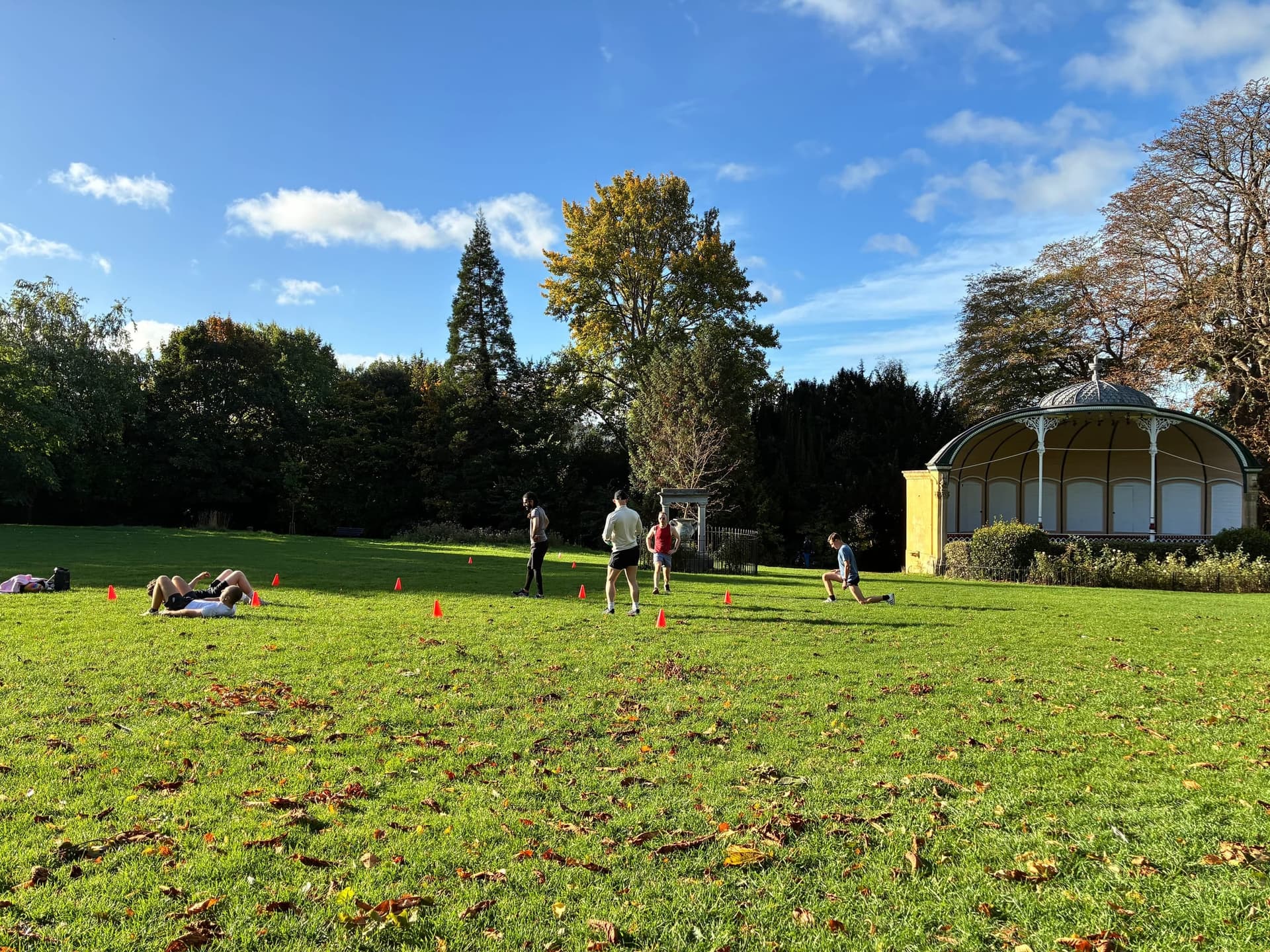 The park bandstand across open grass, autumn colour in the trees.