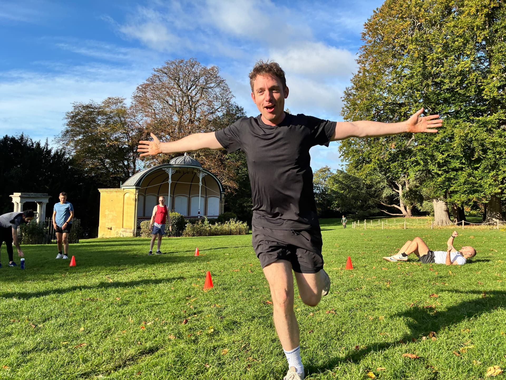 Running full pace across the grass toward the camera, arms wide.