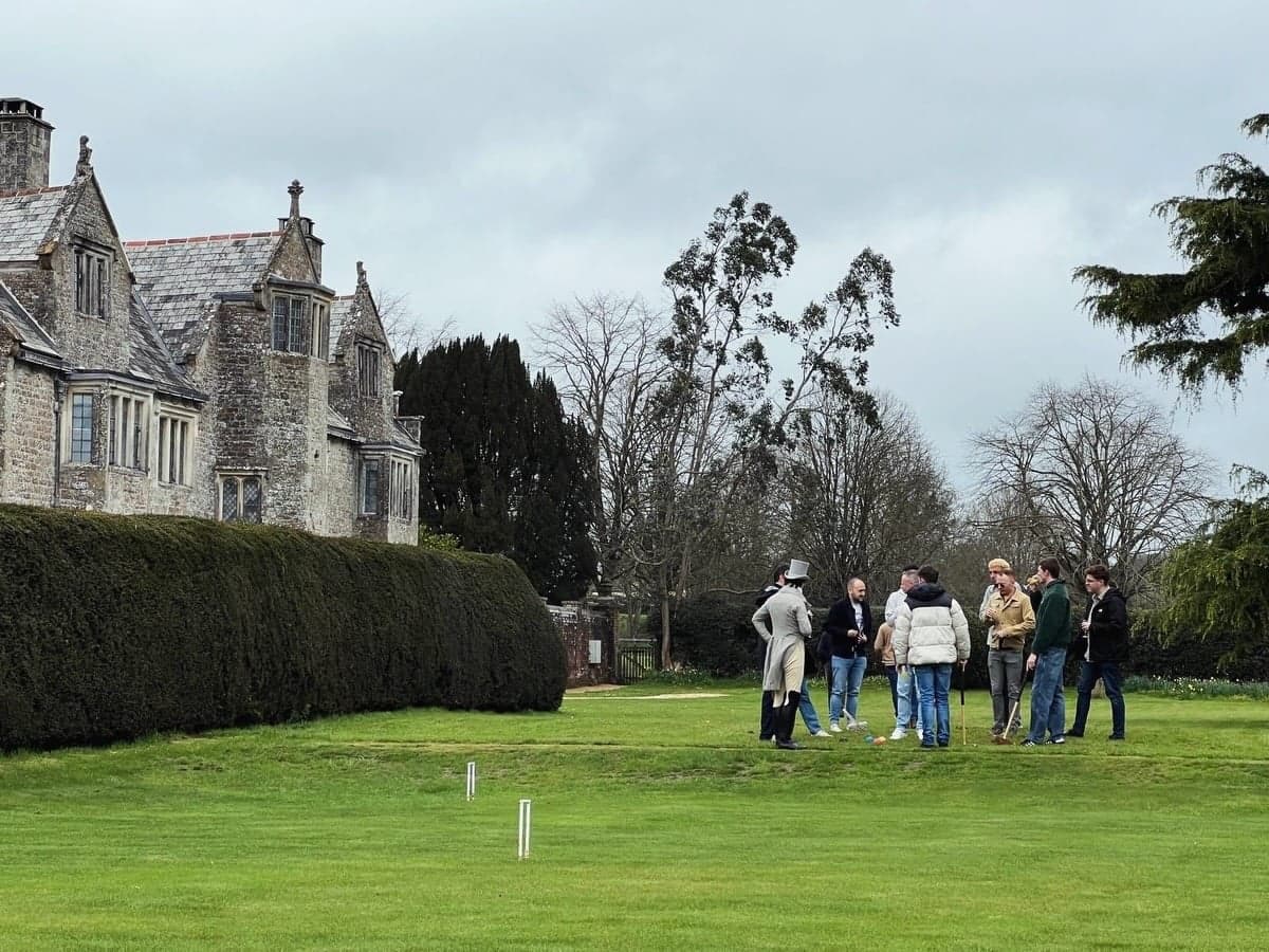 Guests gather on the lawn for a game of croquet by the old manor.