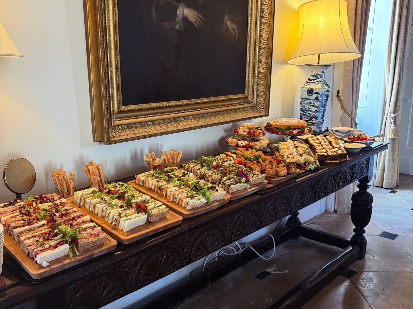 A long table laid out with sandwiches and afternoon snacks.
