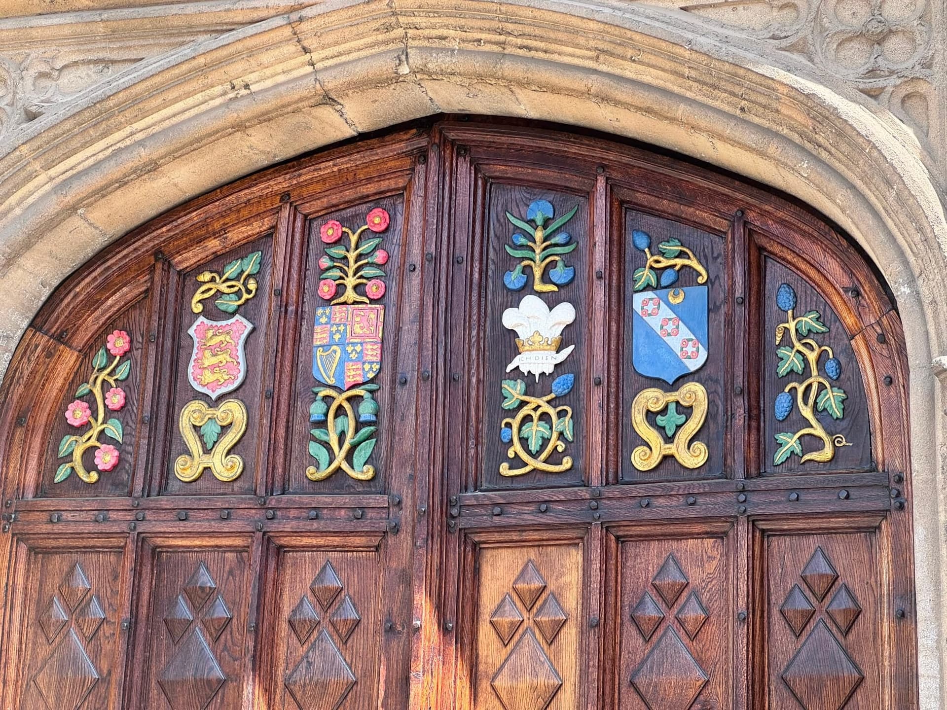 Close-up of a carved wooden door with painted heraldic shields.